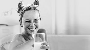 Woman bathes in a YUMA foam bath and drinks YUMA whey